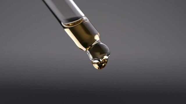 Essential oil dropping from glass dropper in slow motion