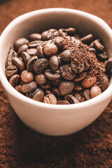 Cup with roasted coffee beans on powder, closeup