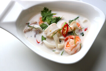 Close up Seafood Coconut Soup served in a boat shaped white bowl Put on the white table Ready to eat Taken from above