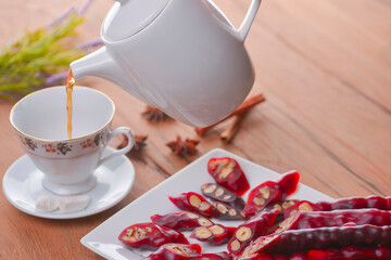 Tasty oriental sweets. Caucasian delicacy churchkhela - georgian nut treats. Served with a glass of tea and a tea pot.