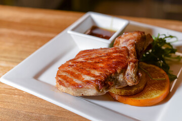 Rack of lamb served with pomegranate seeds and sauce on white plate over red plaid tablecloth. Italian concept.