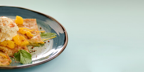 Vanilla ice cream dessert with pineapple fruit and raw mint leaves. Sweet delicious ice cream cold dessert on blue plate