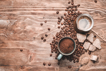 Cup with coffee powder, beans, jezve and sugar on wooden background