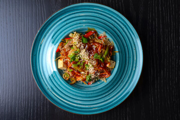 Plate of Traditional Asian salad served in a blue plate at a restaurant over black wooden table.