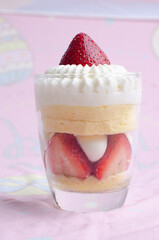 Heart shaped red velvet cake decorated with strawberry and macaron on pink background