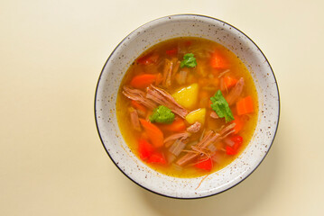 Delicious stew soup with meat and vegetables served in a white bowl over bright pastel yellow background. Healthy diet.