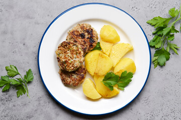 Turkey and zucchini burger garnished with potatoes and parsley. Simple homemade lunch