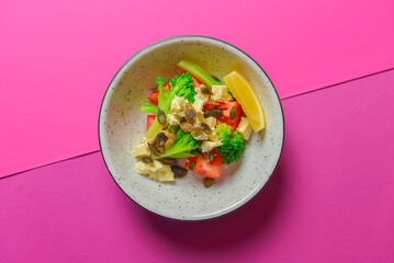 Healthy organic vegan vegetable salad served in a bowl over bright pink background. Spring seasonal concept.