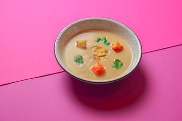 Creme soup with mushrooms served in a white bowl isolated on bright pink background. Copy space banner.