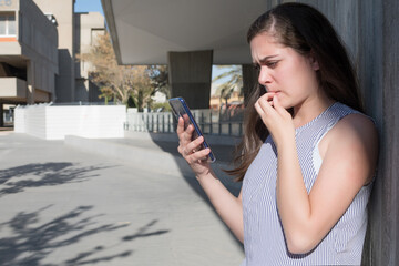 Nervous young woman looking at information on the phone
