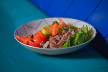 Roasted meat and vegetables salad with tomatoes and brocolli served in a white bowl. Healthy dinner.