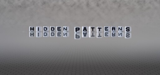 hidden patterns concept represented by black and white letter cubes on a grey horizon background...