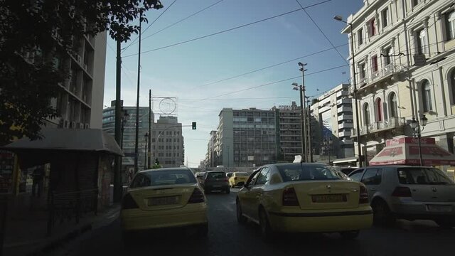 ride with car in Athens city centre Omonia square , yellow greek taxi at front busy day traffic building around greek architecture urban lifestyle everyday life