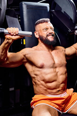 Handsome male bodybuilder in gym. Big strong man during training in the gym. Guy with big muscles...