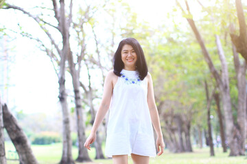 Beautiful asian woman in white dress relax and smiling in nature park. Thai girl or Chinese Girl enjoy on holiday in garden