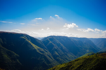 Natural view of the folded mountains and lush green valleys with clear sky and clouds of...
