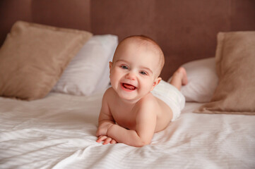 baby in a diaper
 lying on the bed at home smiling