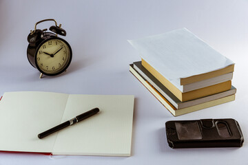 Still life con reloj antiguo sobre escritorio con libros, reloj despertador, gafas y fondo negro o...