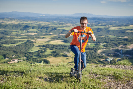 young man with an electric scooter on the mountain going up a hill