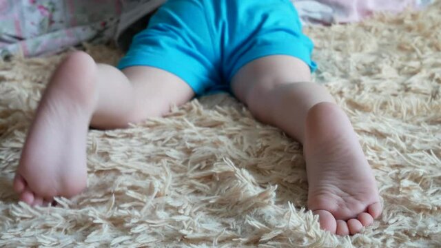 Two feet of a little boy lying on a soft plaid