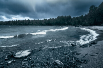 An autumn storm on Lake Segozero in the Republic of Karelia. Dense frowning clouds and strong winds drive waves in the bay.

