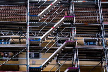 Building under renovation surrounded by scaffolding with exposed stairs and floors