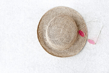 Straw hats for woman and pink sunglasses on concrete background.
