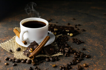 Coffee drink and coffee beans and chocolate on rustic dark background. Sackcloth texture.