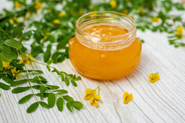 Honey with acacia blossoms on a light wooden background