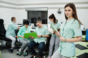 Medical theme .Portrait of female doctor with clipboard against group of doctors meeting in the mri office at diagnostic center in hospital.