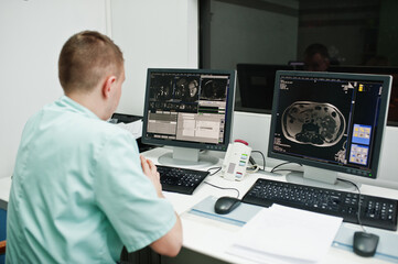 Medical theme. Doctor in the mri office at diagnostic center in hospital, sitting near monitors of computer with human brain on it.