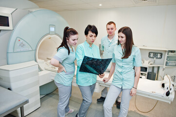 Group of doctors near magnetic resonance imaging machine at hospital.
