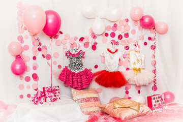 
Decoration for a dog’s birthday party, pink balloons, elegant dresses for dogs, boxes and pillows made of sequins.