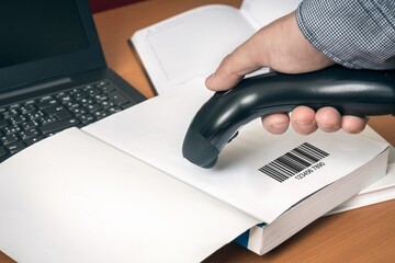 Man with scanner scans barcode in a book