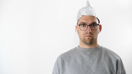 Portrait of serious attractive man in foil hat and glasses. Emotional handsome guy with a tinfoil...