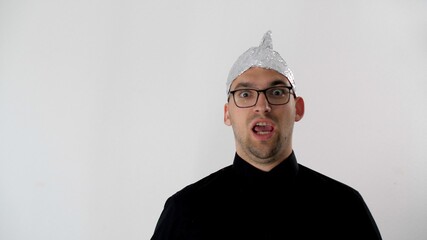 Frightened man screams that 5G radiation waves penetrate his head. Paranoid in a foil hat. White man in a tinfoil hat. Irrational fear of a non-existent problem. Protective helmet to the brain.