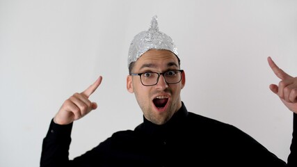 White man in a foil hat smiles and joyfully points his fingers at the tinfoil hat. 5G tower...