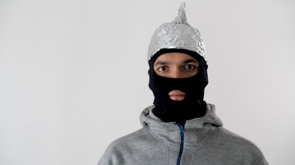 Portrait of a white frightened man in a black balaclava and a tinfoil hat waved off the 5G waves....