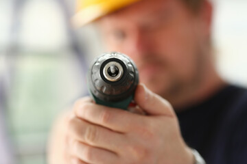 Fototapeta na wymiar Arms of worker using electric drill closeup