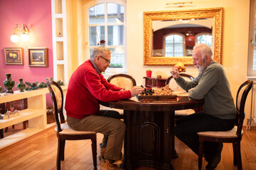 Two senior men outmaneuvering each other while playing chess