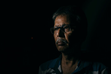 Portrait of a sad Indian Bengali man in light and shadow.