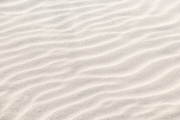 Fototapeta na wymiar Beautiful light sand texture. Wave texture on the sand. Sandy beach for a background. Top view.