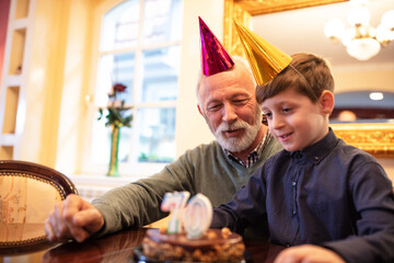 Cute boy celebrating a birthday with his grandfather