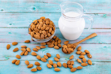 almond nuts in spoon and almond milk in glass on blue wooden table