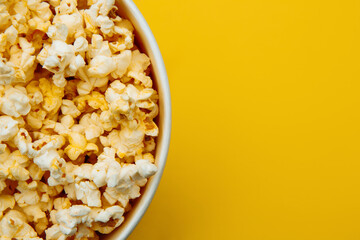 Popcorn closeup viewed from above on yellow background. Flat lay of pop corn bowl. Top view.