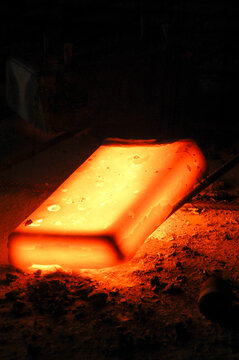 Lingote de metal al rojo vivo sobre malla met&aacute;lica en terreno arenoso