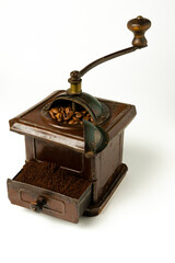 Molinillo de café marrón con granos de café en el interior y café molido en cajón sobre fondo...