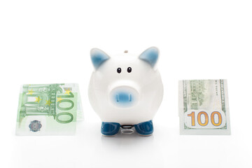 Piggy bank standing between dollar and euro banknotes at white background 