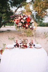 A banquet on nature, a table with a white tablecloth, vintage plates with a gold rim, wine glasses,...