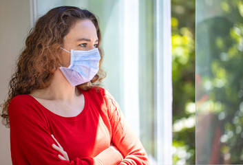 Young woman in isolation at home near window